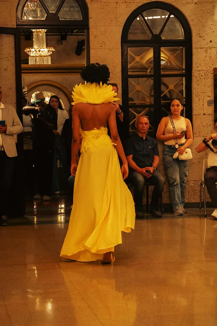 Salida 07: el vestido canario de espaldas, con la espalda descubierta y el hombro emplumado.